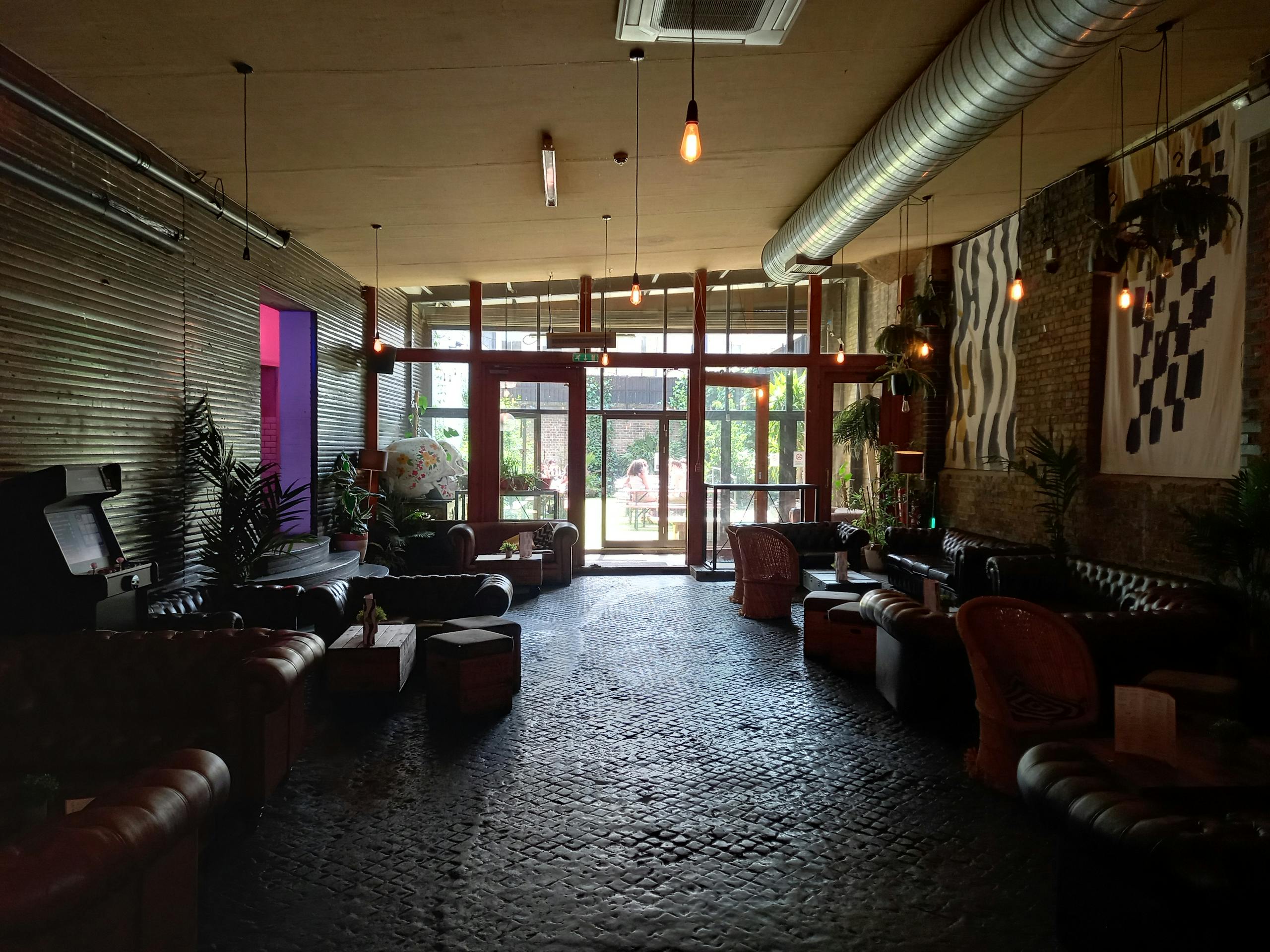 Stylish urban lounge with leather sofas, plants, and industrial decor for relaxation.